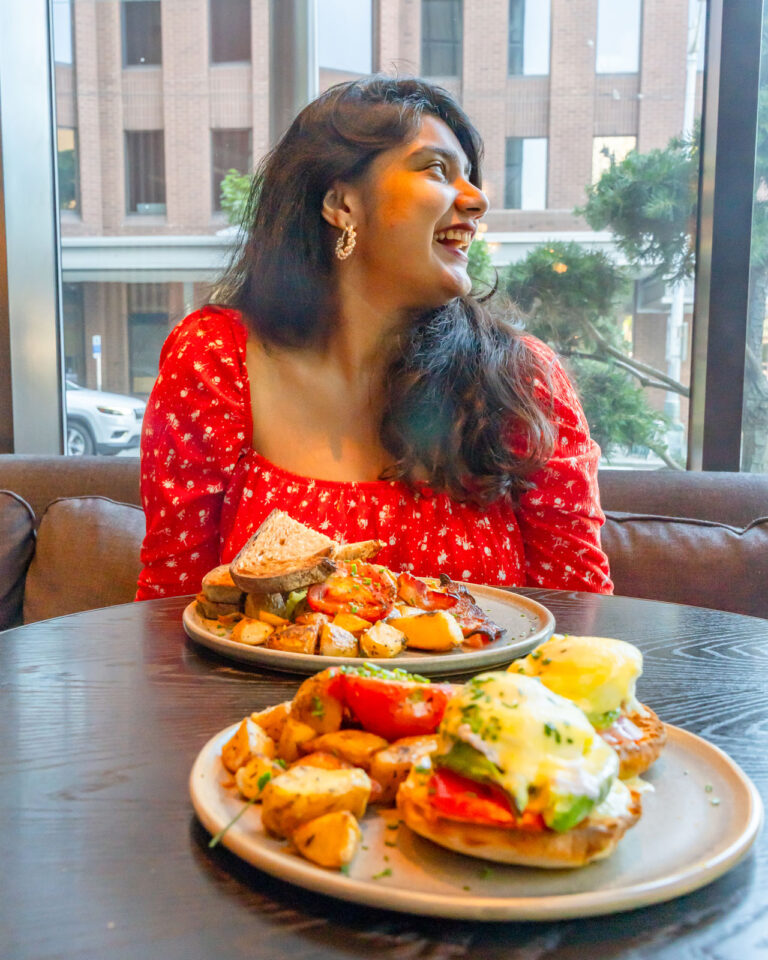 A woman sitting at a table with two plates of food at Conversation