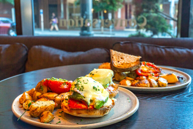 Two dishes containing eggs benedict and a sandwich at Conversation