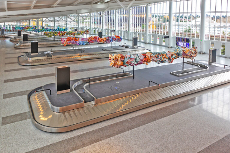 The baggage claim at the new International Arrivals Facility with colorful art installations in the center of each carousel.