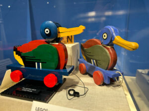 A museum exhibit showcasing the original wooden duck pull toy released by LEGO in 1935 next to a 2020 replica built with LEGO bricks.