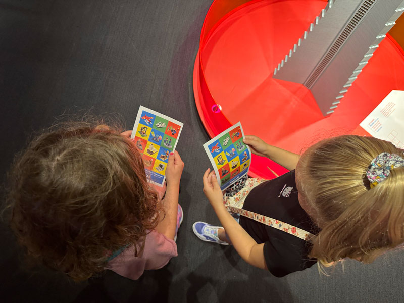 Aerial view of two young girls studying a colorful scavenger hunt sheet. 