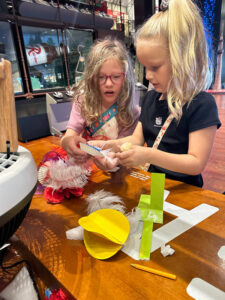 Two girls experiment with placing different materials over a fan to see which have more of a propensity to "fly".