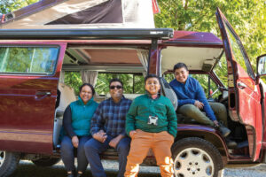 A photo of four family members sitting in a red camper van.