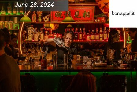 Mixologist makes a drink at a bar that is lit in red lighting