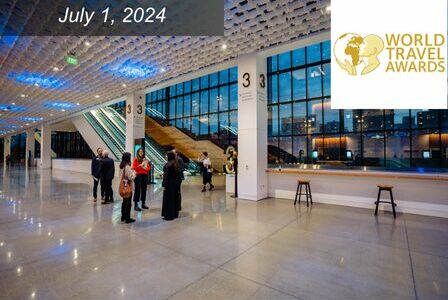 A group of people wearing business casual stand in a big room with expansive windows showing a view of downtown Seattle