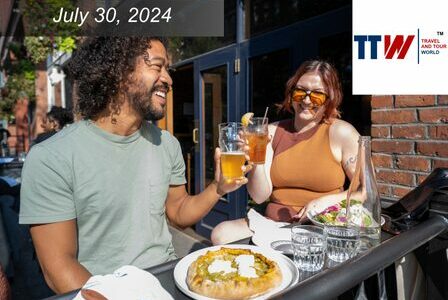 Two people, a Black man and a white woman, toast beers at an outdoor patio
