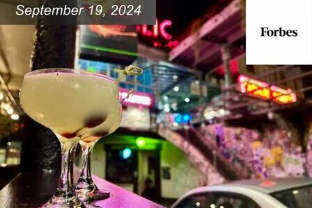 Two cocktails on a bar counter in a lively, colorful setting in Pike Place Market