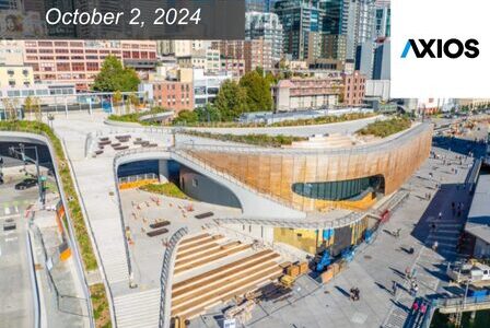 Aerial view of a modern rooftop park with pathways, trees, and seating areas, surrounded by urban buildings.
