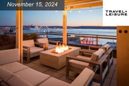 Inn at the Market. A cozy rooftop patio with modern seating surrounds a lit fire pit. A waterfront view with a Ferris wheel and a neon 