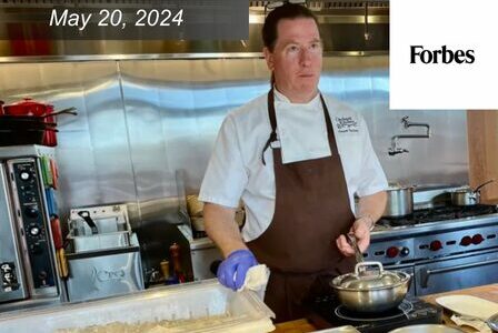 Chef Vincent Nattress stands at a counter with a tub of shellfish nearby