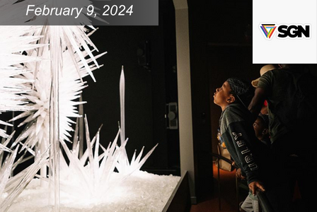 A child gazes in awe at a large, illuminated crystal art installation in a dimly lit space. The display date is February 9, 2024, with the SGN logo visible in the corner.