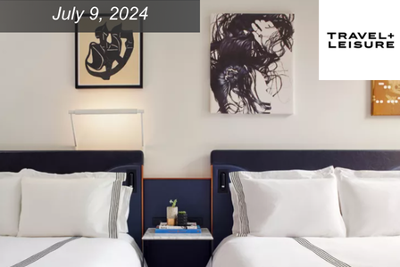 Hotel room with two beds with white sheets and navy headboards.
