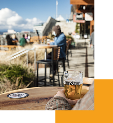 A person holding a glass of beer while sitting on the outdoor patio at Old Stove Brewing