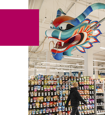 A person walking under a paper dragon in front of displayed snacks in Uwajamaya
