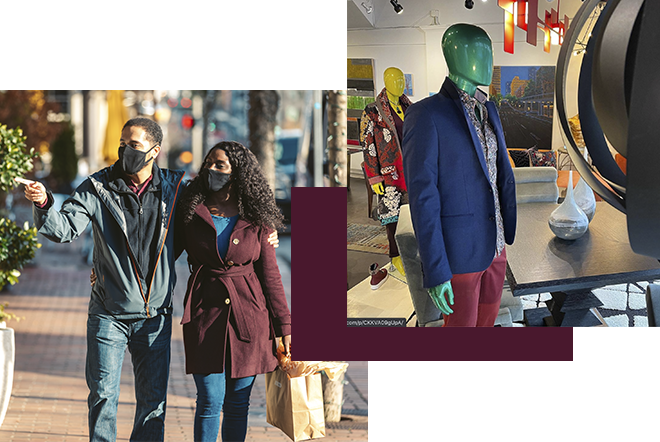 A couple wearing masks, carrying shopping bags, walks on a sunny street. Nearby, a store window displays mannequins dressed in colorful outfits, including a blue blazer with a tie and burgundy pants.